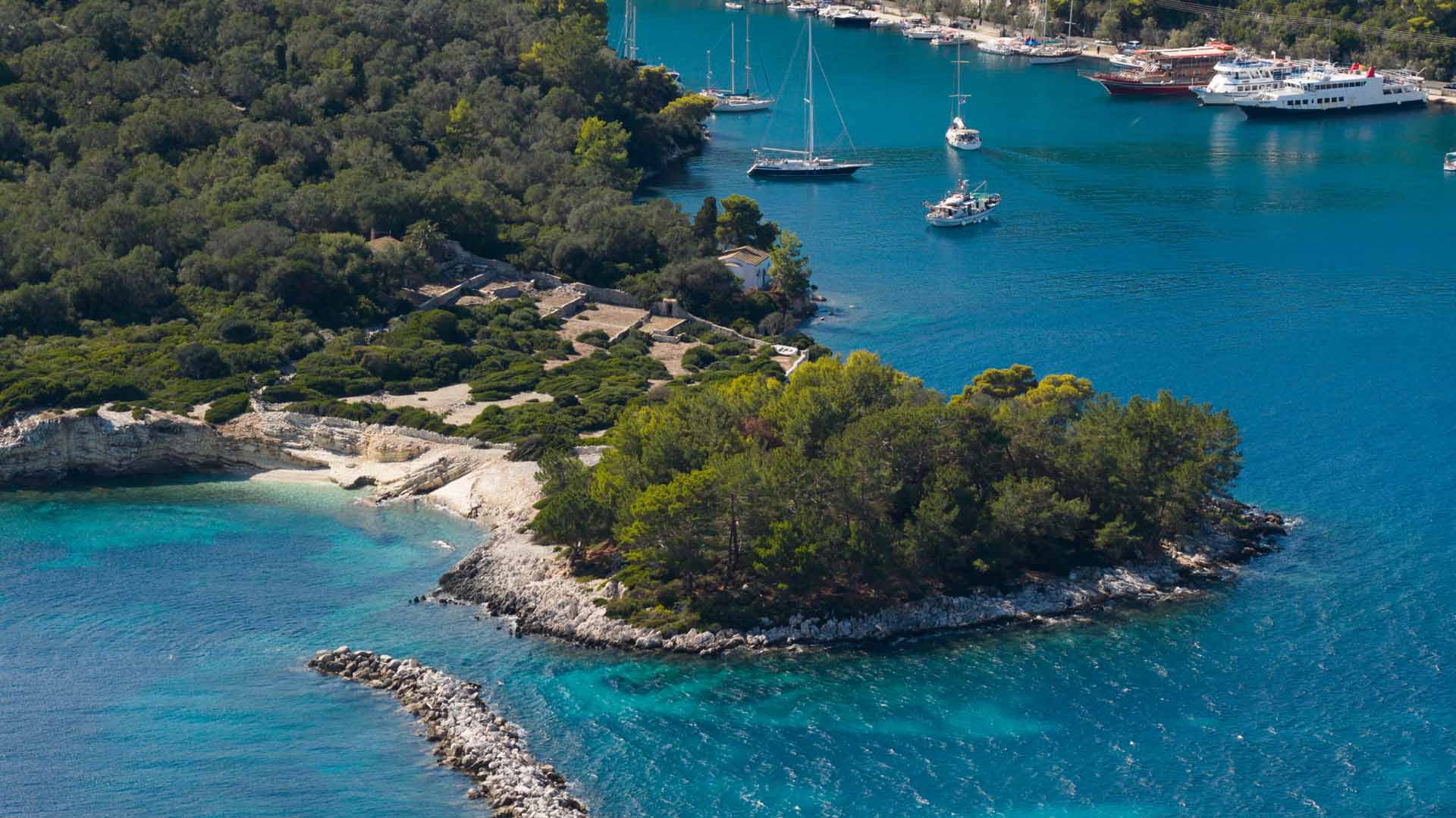 Small harbour, wooded slopes and clear water on Paxi