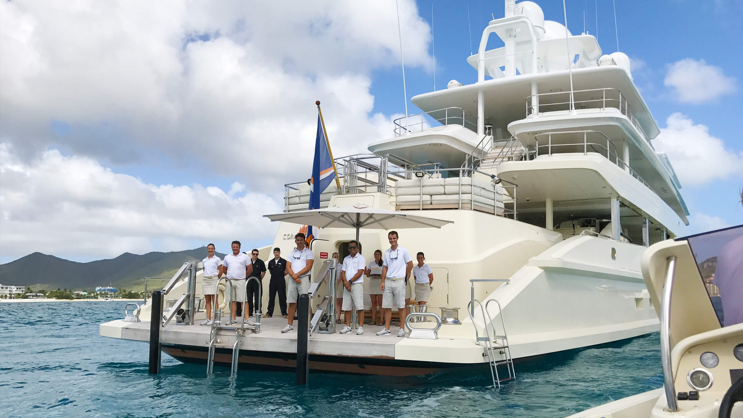 Crew and project team gathered on the stern of a completed custom yacht