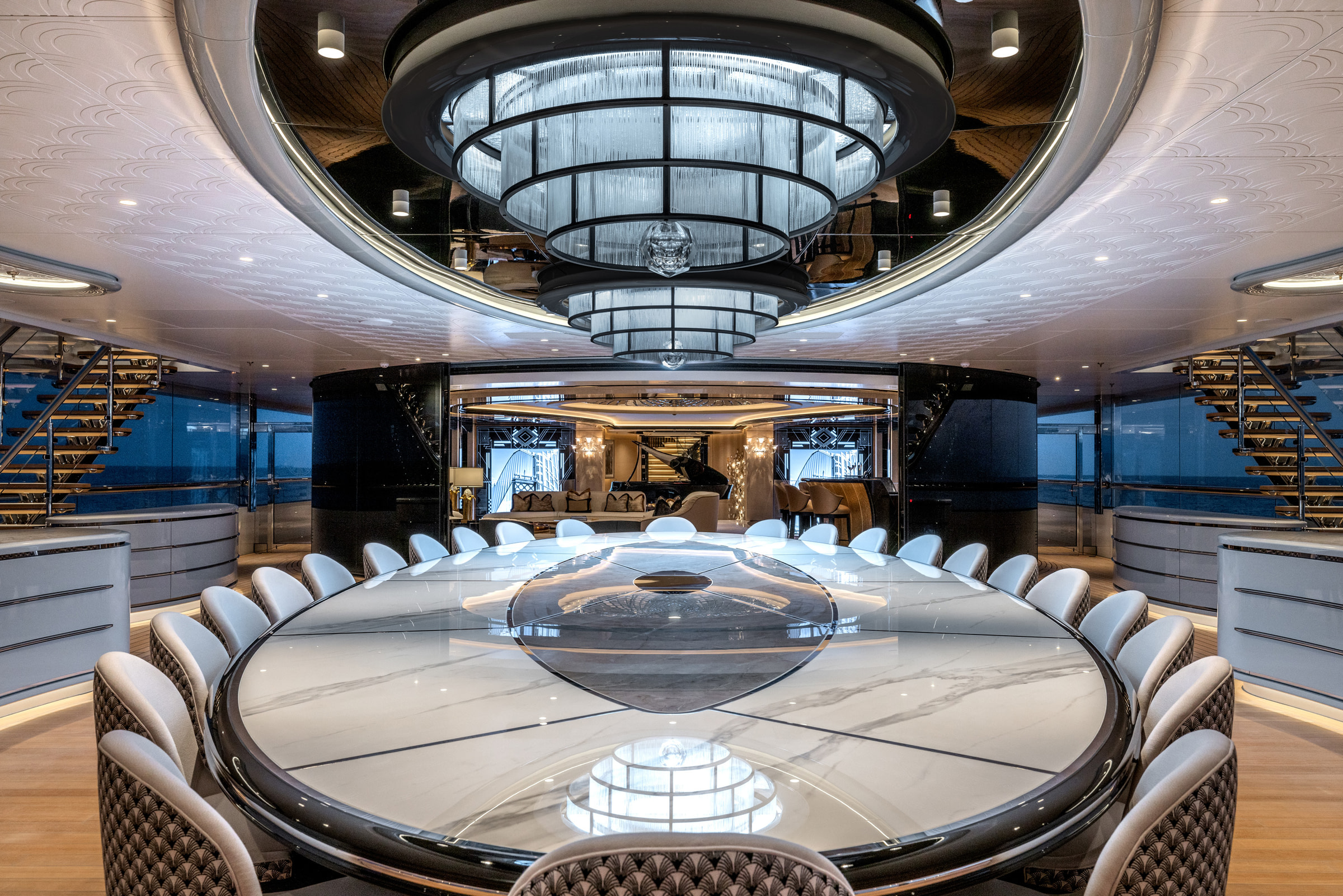 KISMET dining salon with a sculptural chandelier and symmetrical staircases