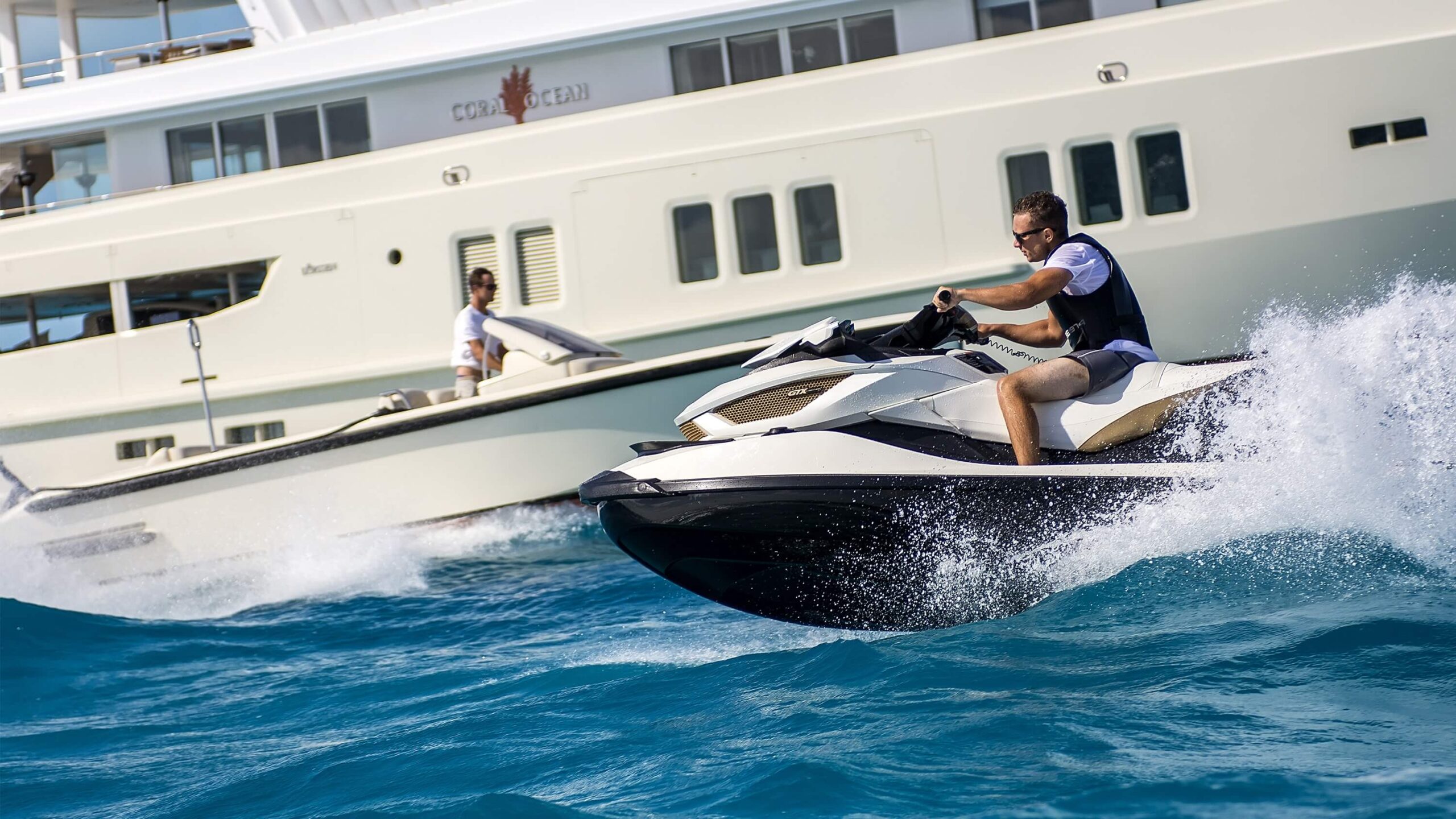 Personal watercraft operating beside a large custom superyacht