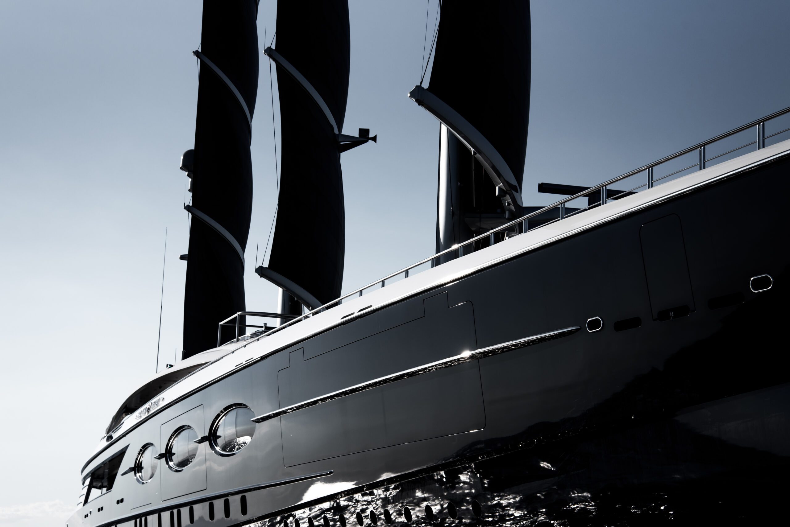 Low-angle detail of BLACK PEARL’s dark hull, rotating masts and black sails