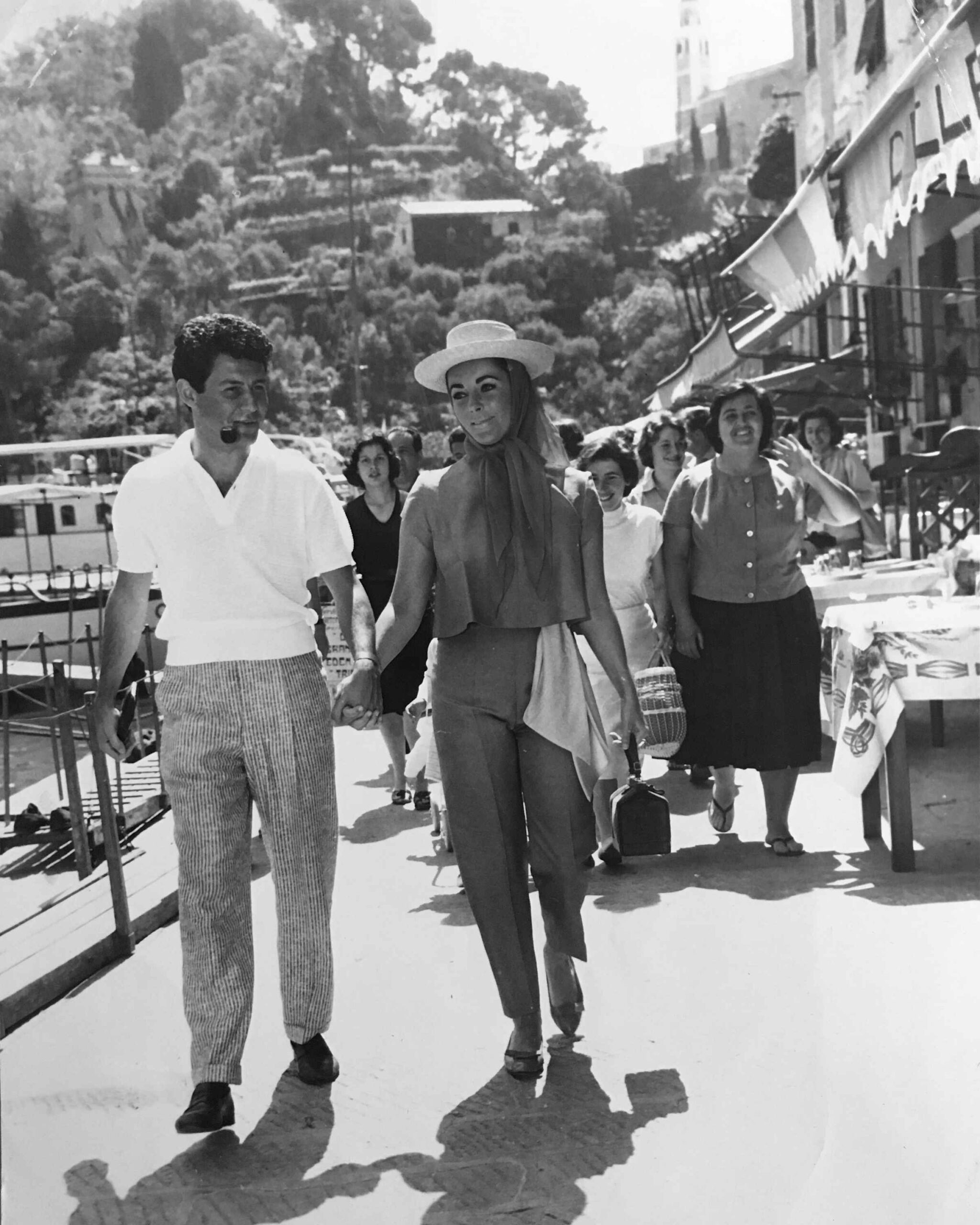 Historic black-and-white photograph of visitors walking along the Portofino waterfront