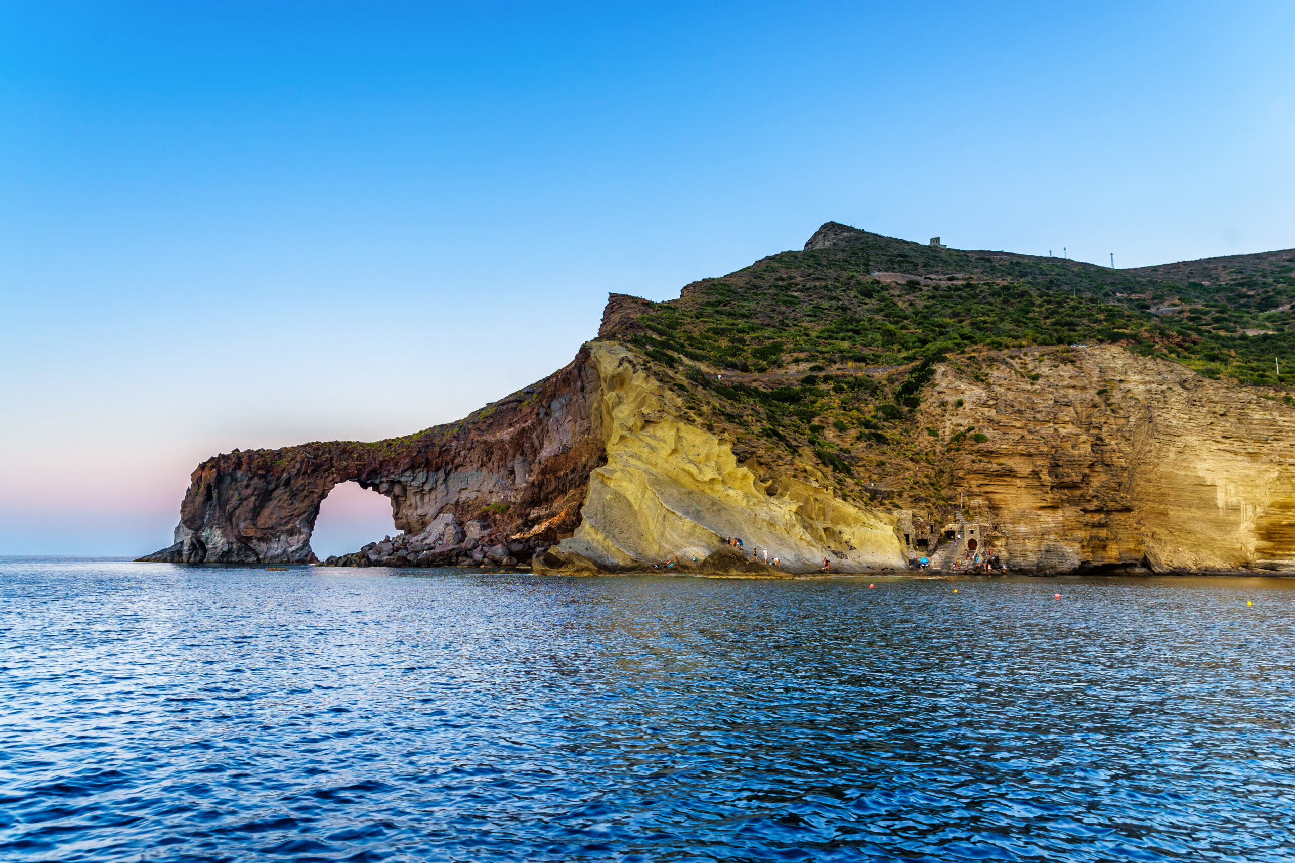 Natural rock arch and clear water along the coast of Salina