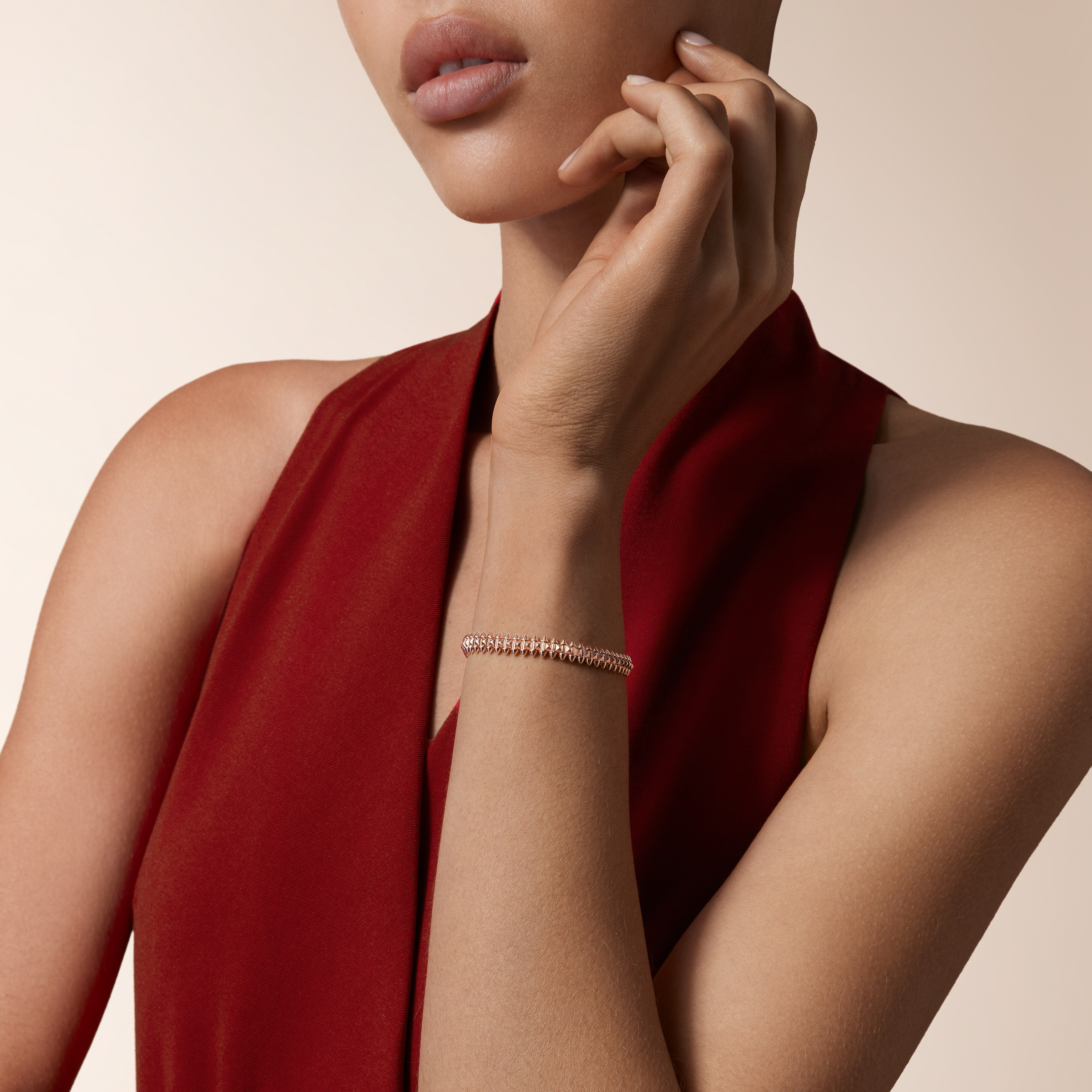 A rose-gold-coloured Clash bracelet worn beside a red garment in official styling