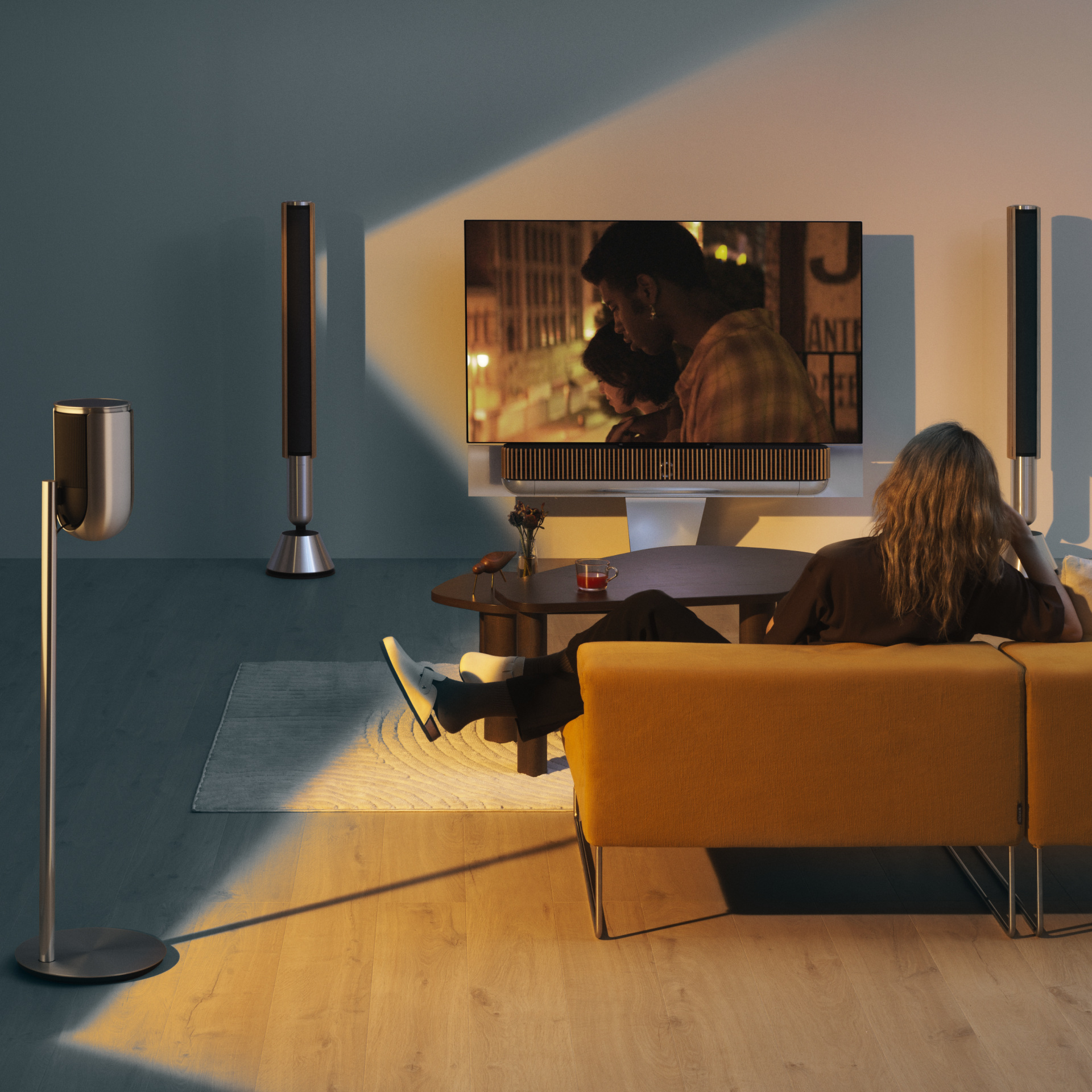 Official room photograph showing Beosound Theatre below a screen with companion speakers