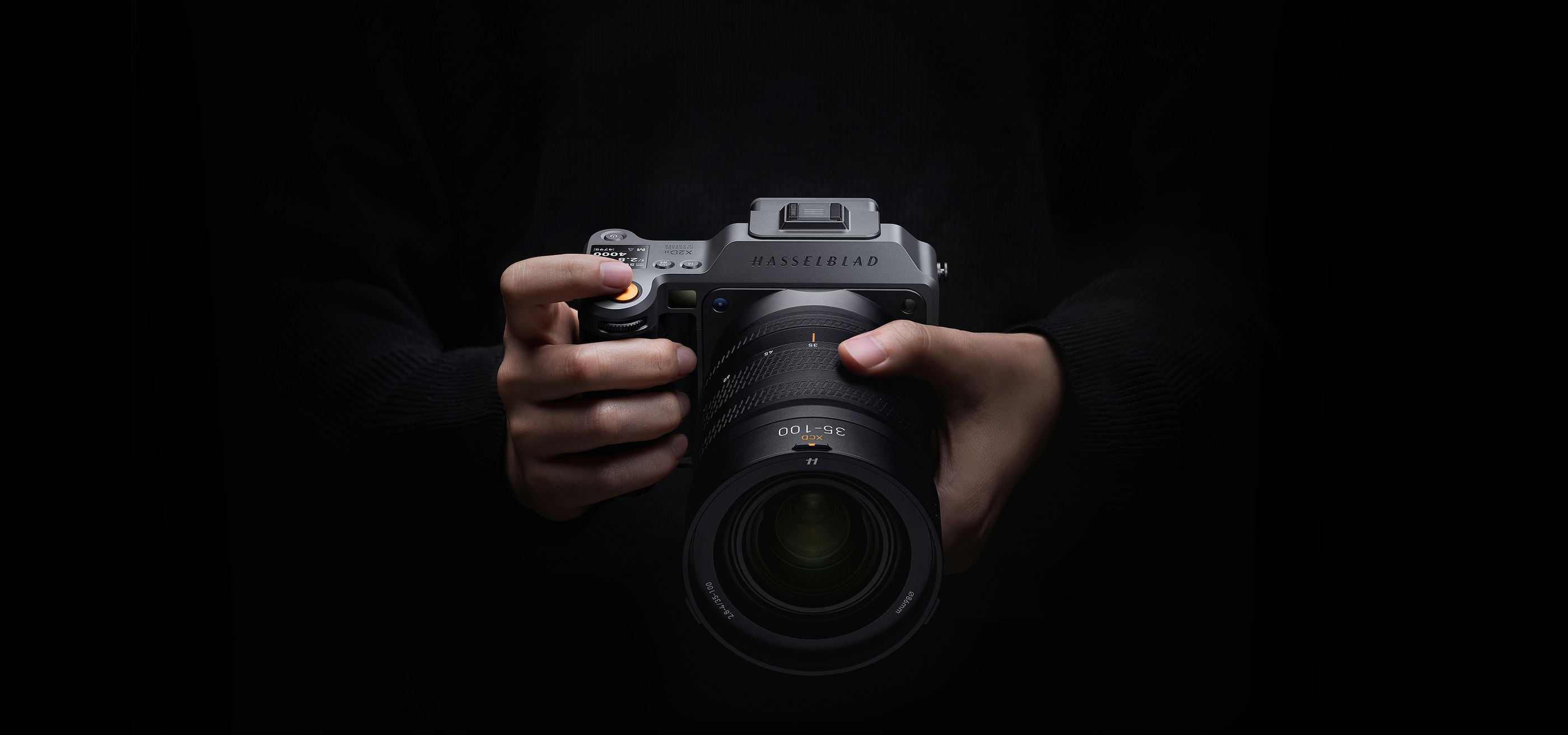 Official X2D II 100C campaign photograph showing the camera held at the front