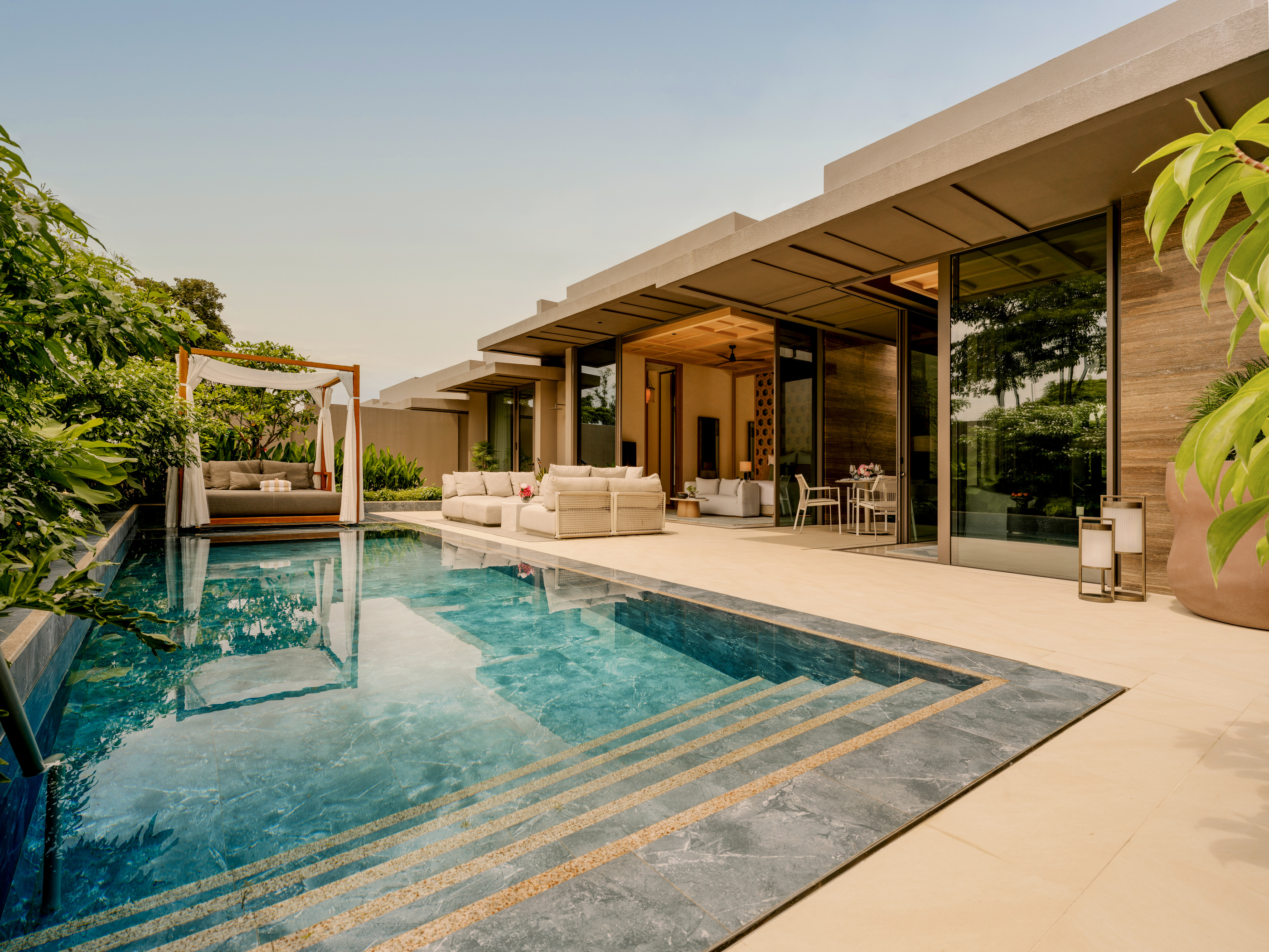 A villa pool beside a covered terrace in official Raffles Sentosa photography