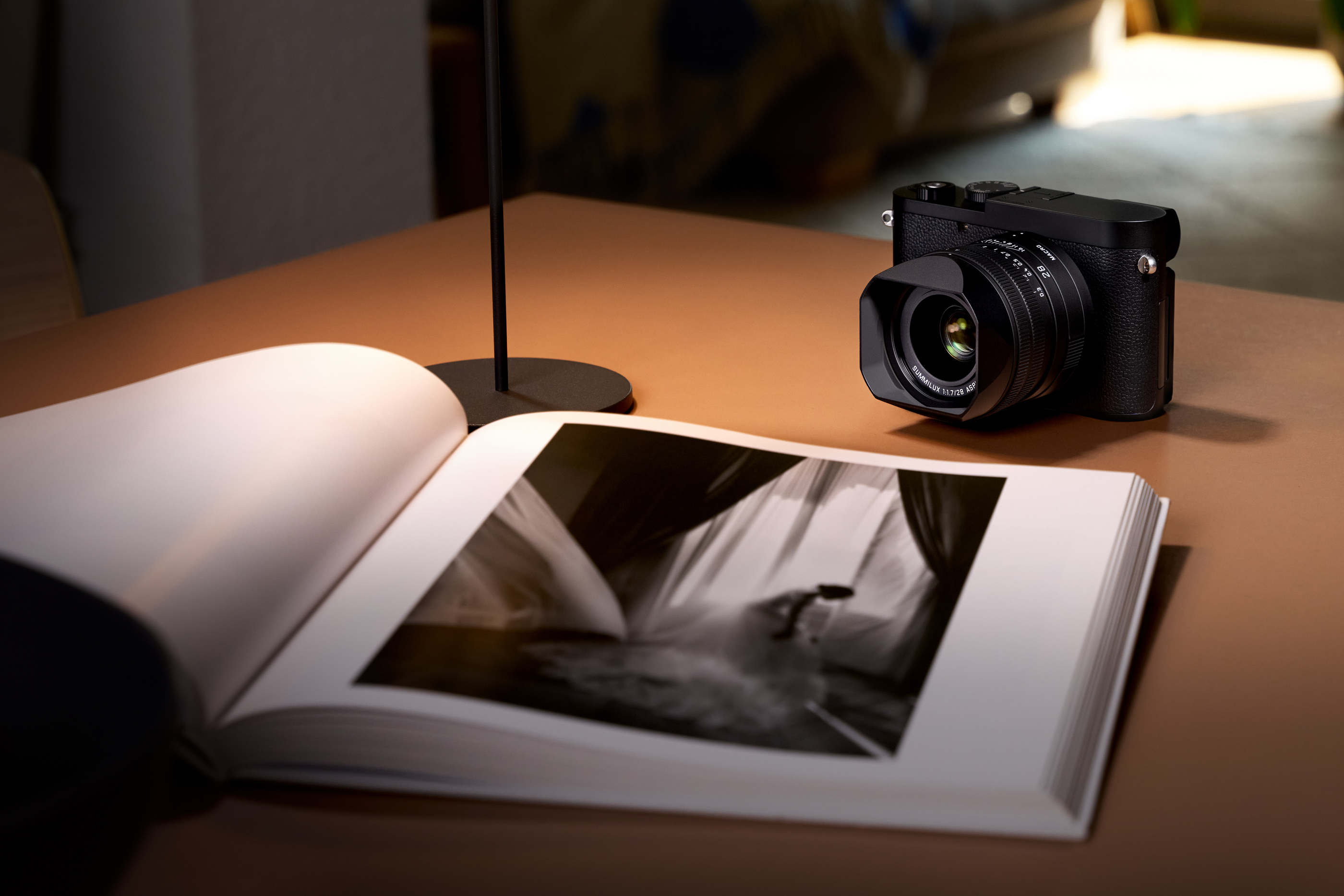 Q3 Monochrom beside an open photography book in official Leica imagery