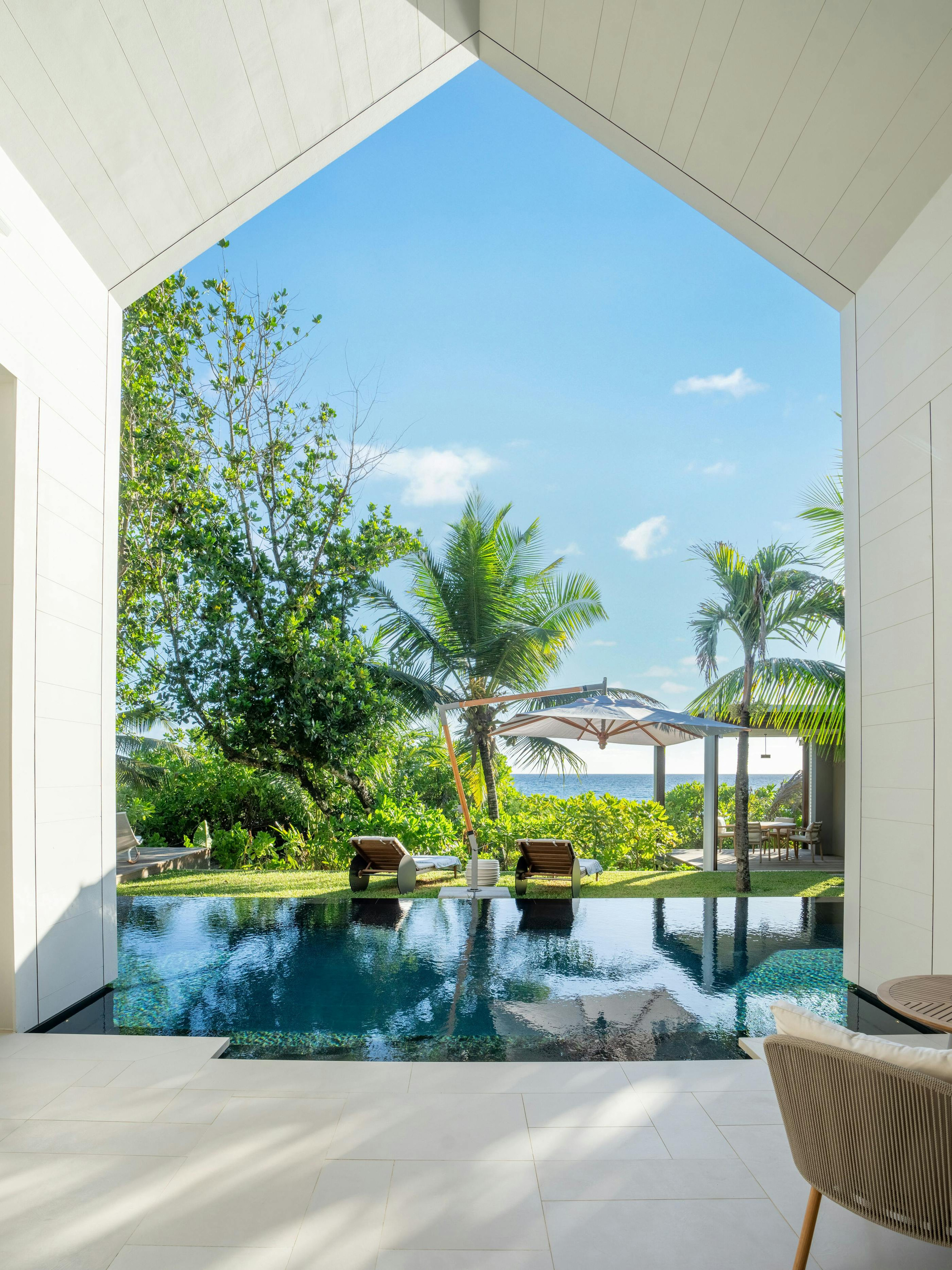 A view through the beach-villa opening towards its pool and garden.