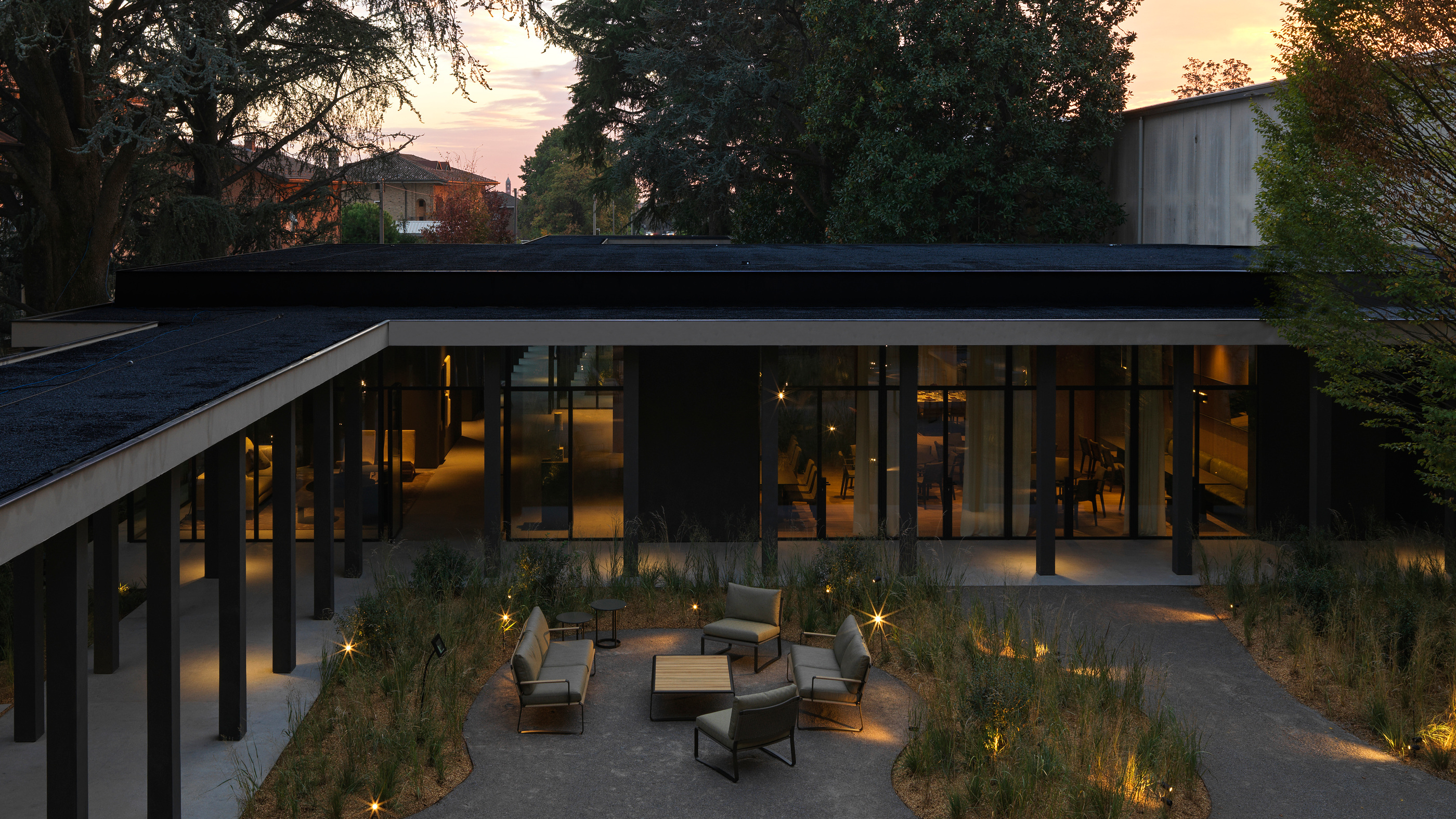 Molteni&C Pavilion at dusk, with the planted courtyard between lit rooms.