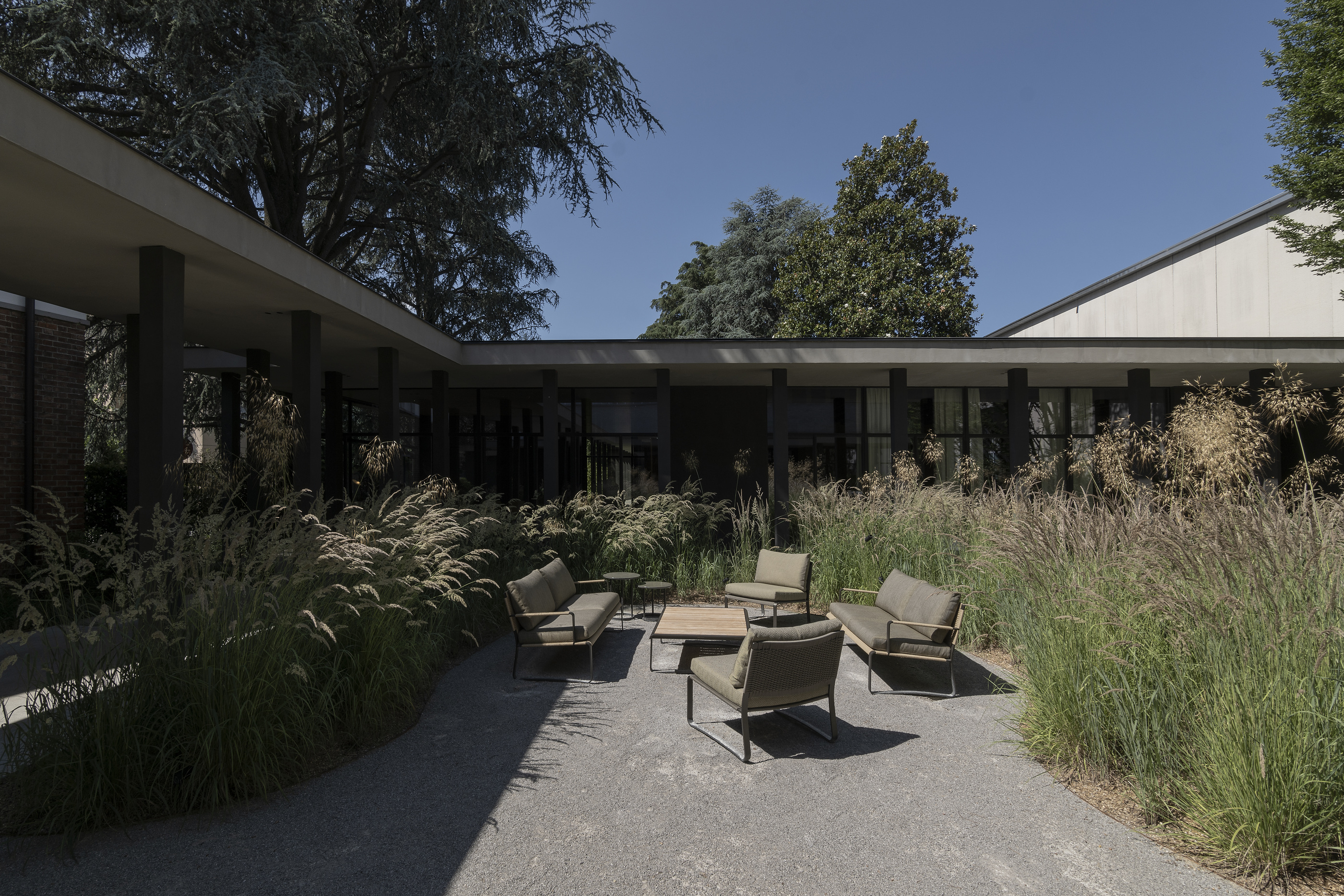 The courtyard and outdoor seating beneath the trees at Molteni&C’s Giussano compound.