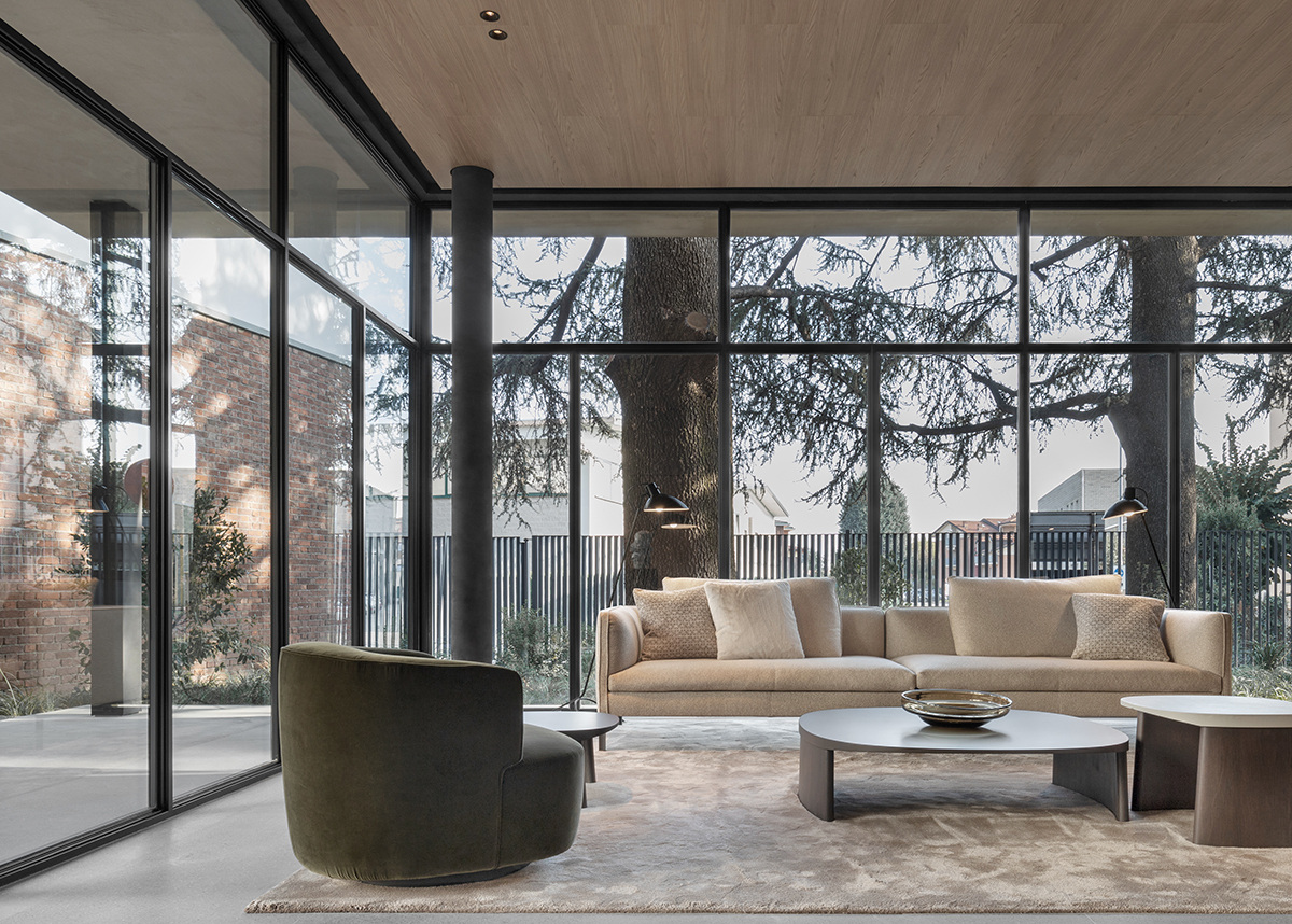 A furnished interior looking through glazing towards the Pavilion garden. Photograph by Max Zambelli, courtesy Vincent Van Duysen.