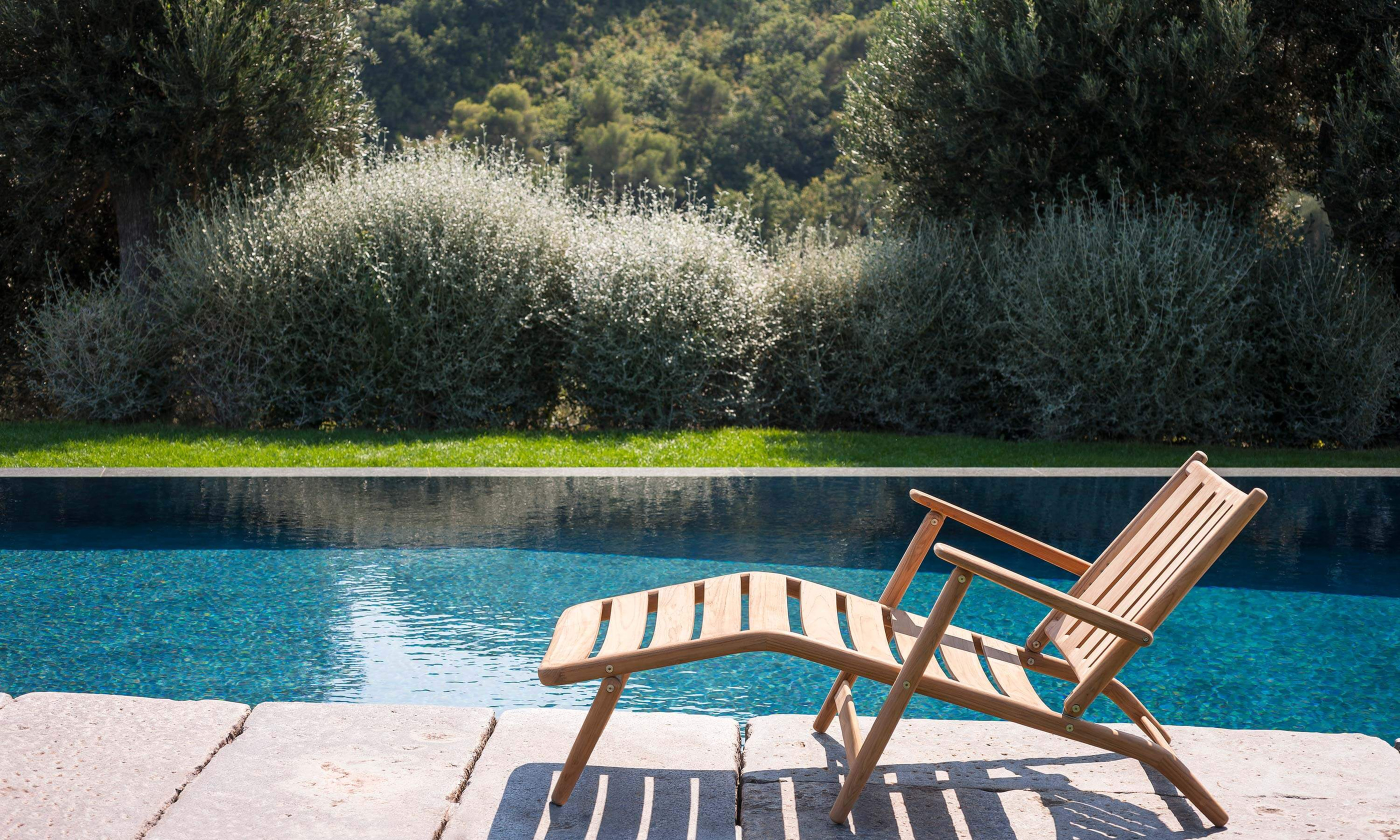 A Levante recliner beside a pool, with the landscape beyond.