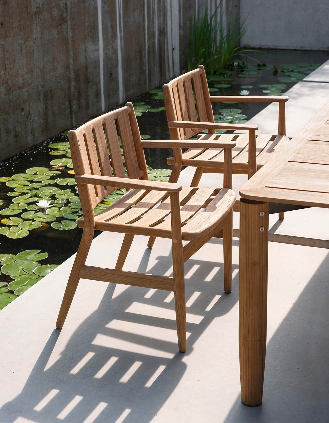 The teak chair frames in a repeated outdoor seating arrangement.