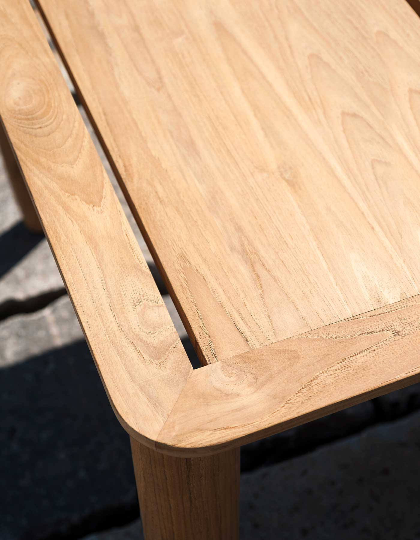 Close view of a teak tabletop corner and its slatted construction.