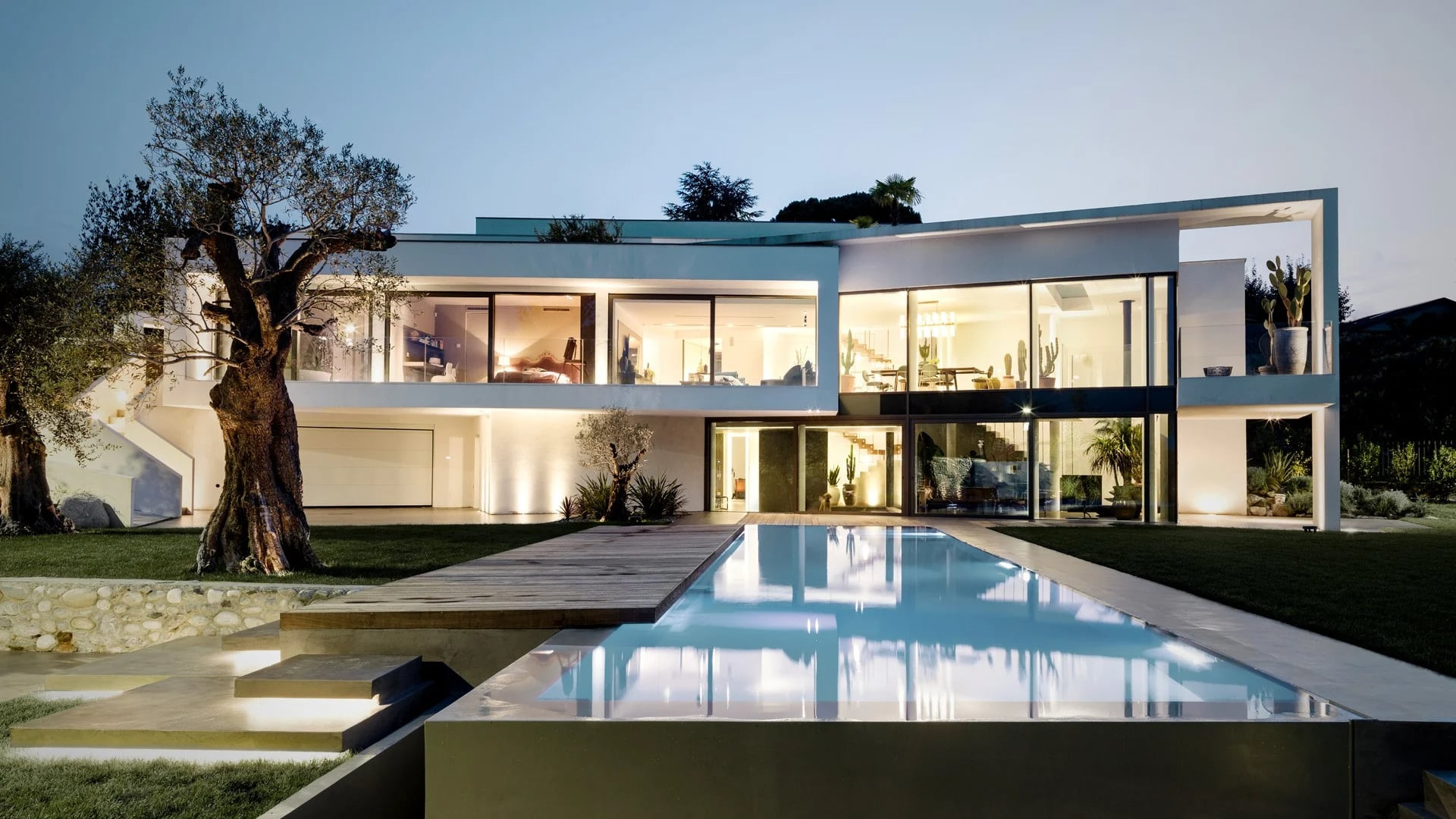 Villa Aghe reflected in its pool in the official evening exterior.