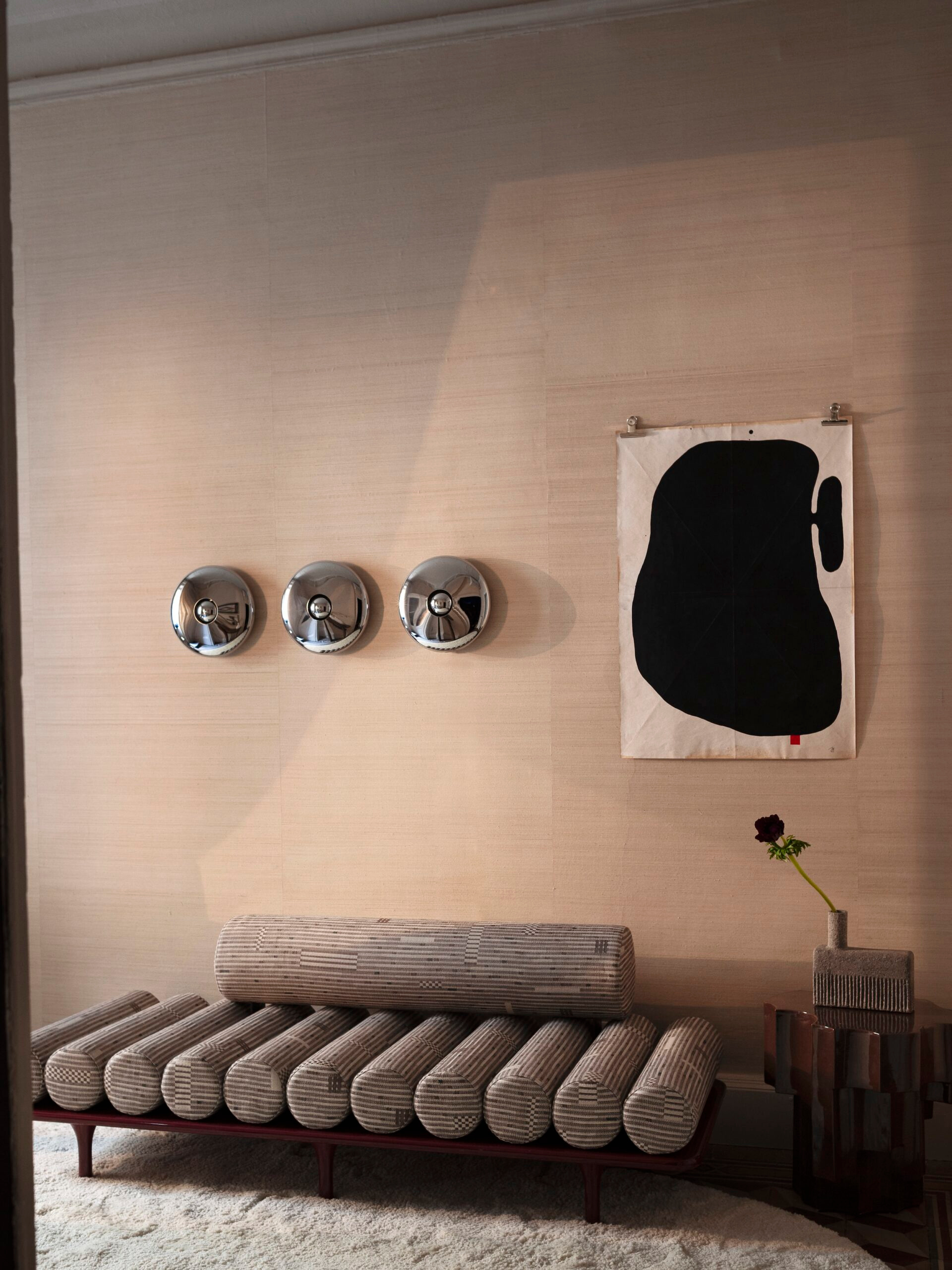 A low seat and artwork against a textured wall in the Tacchini interior.