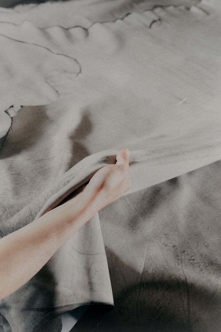 A hand examines a leather surface in the official production photographs.