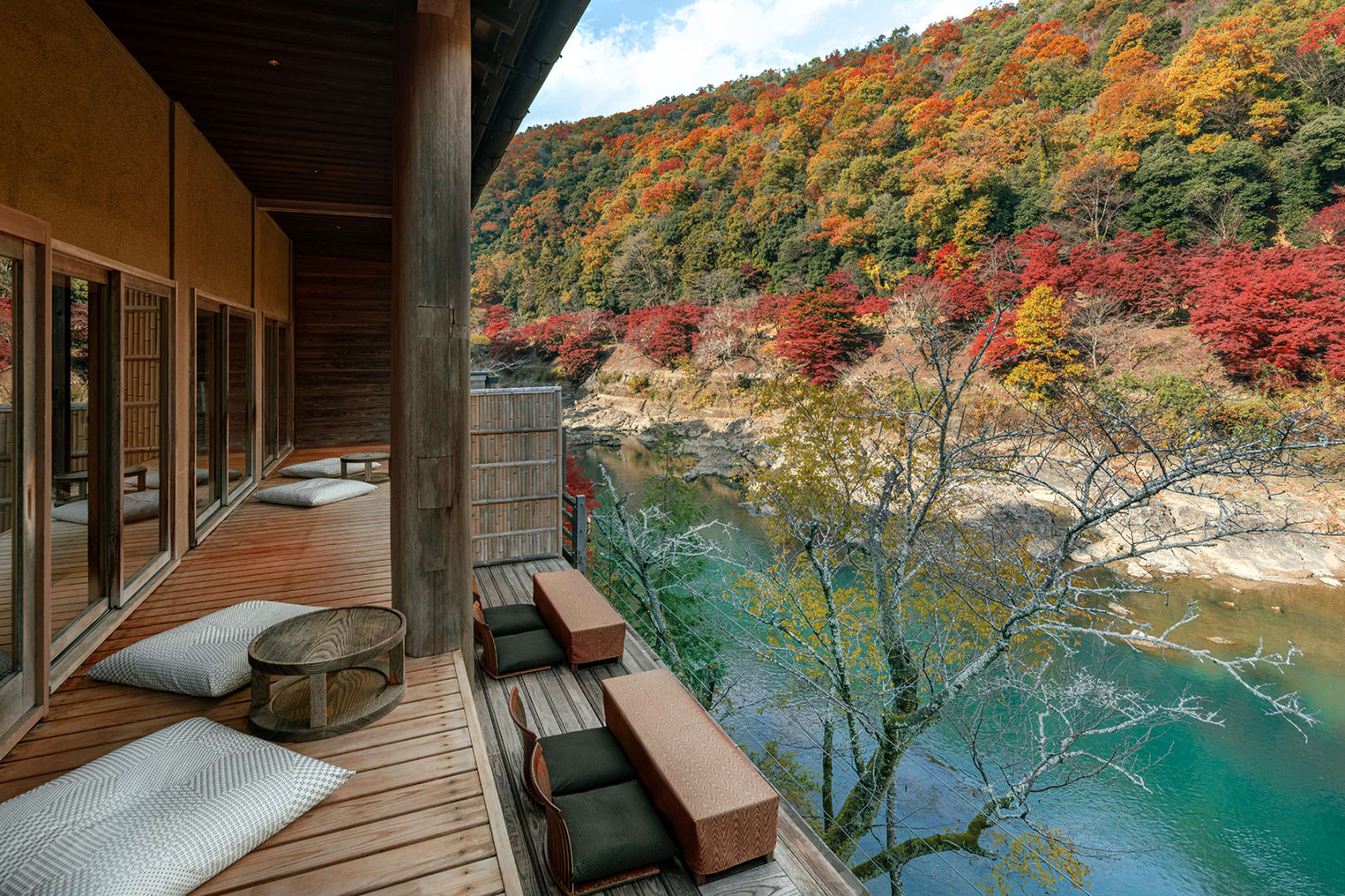 A riverside sitting space at HOSHINOYA Kyoto, photographed with autumn foliage in the official gallery.