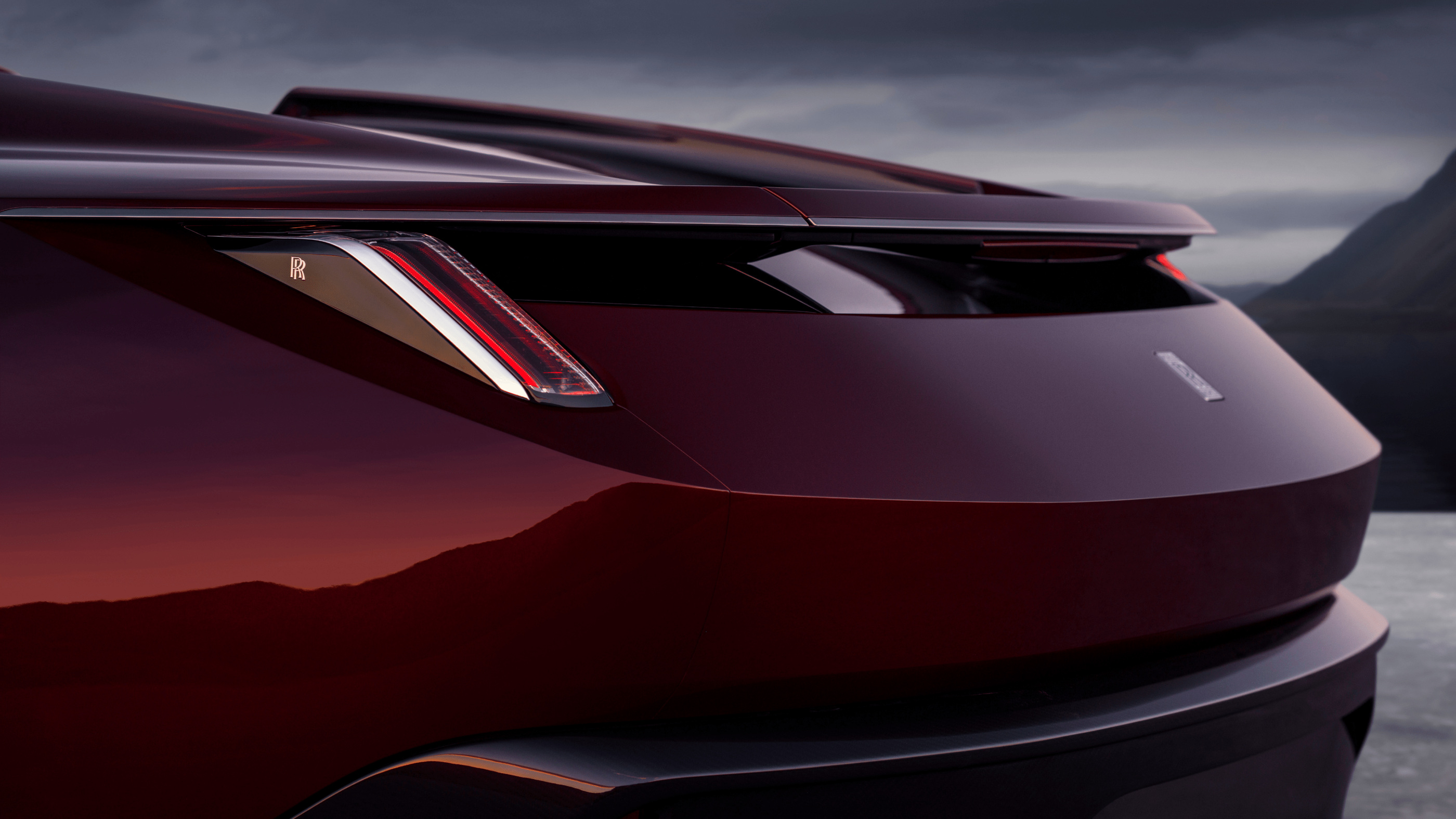 The rear lamp and changing highlights across the dark red coachwork.