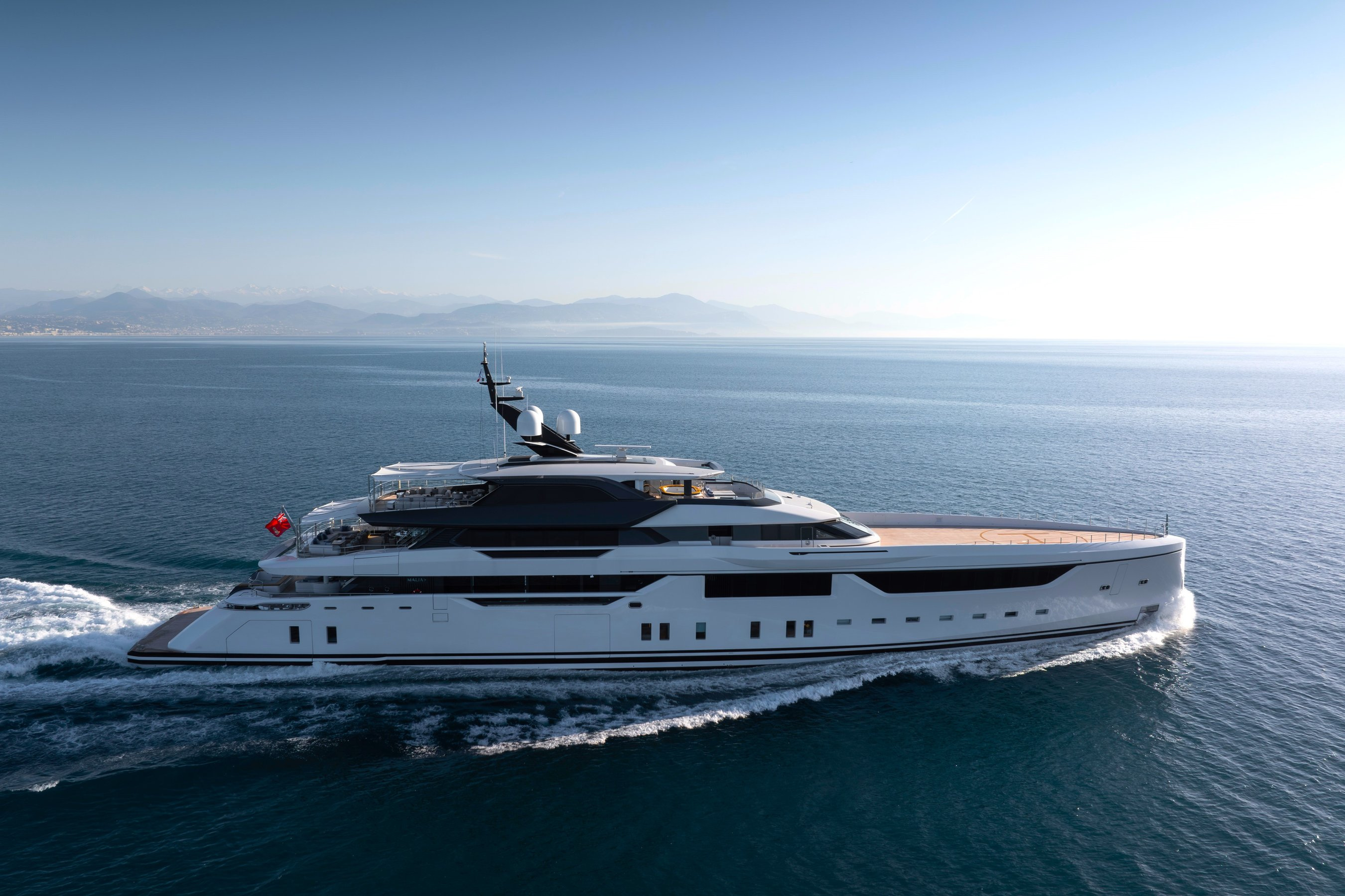 MALIA in profile: the white hull and stepped outdoor decks seen from the water.
