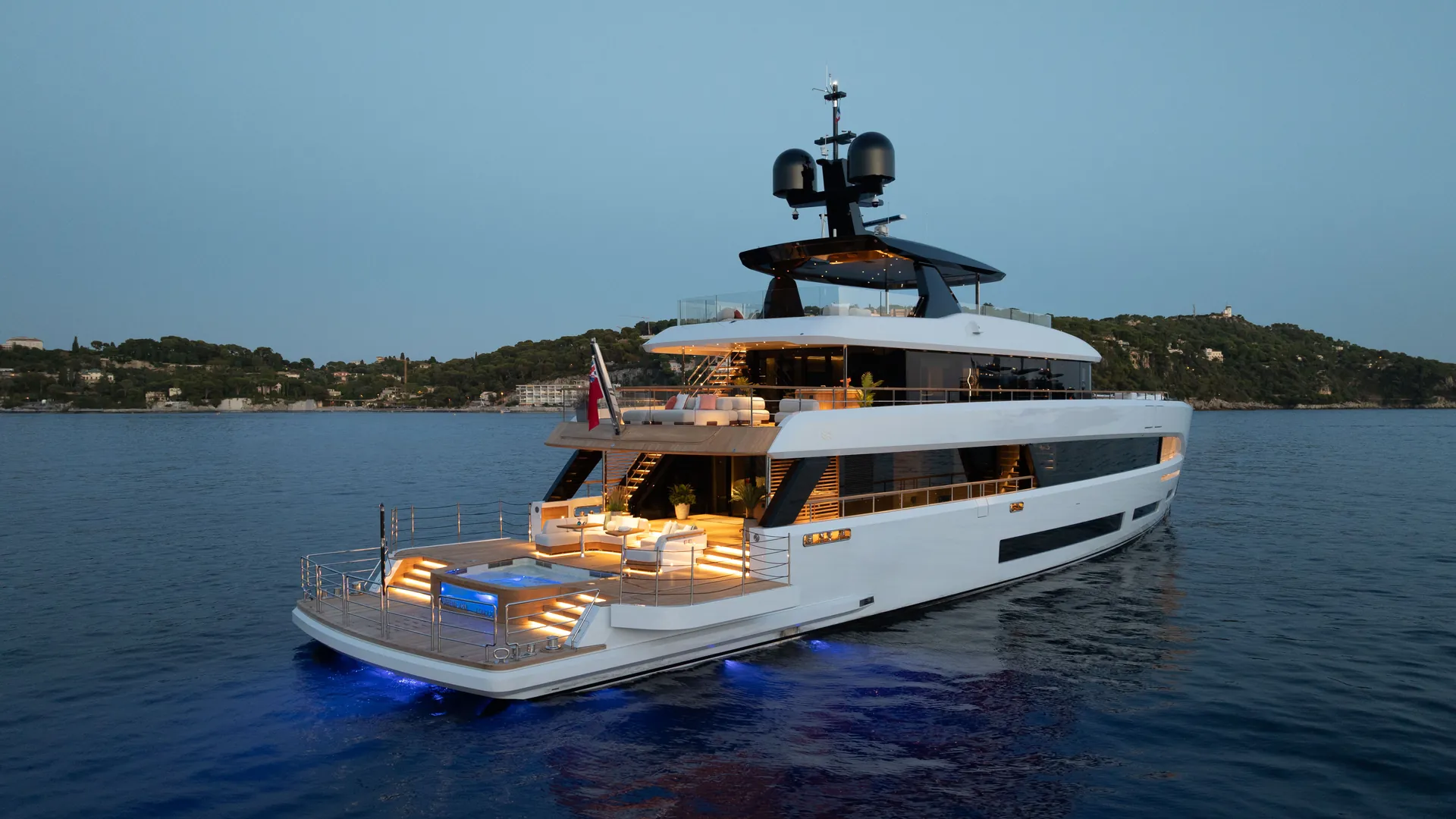 The Sirena 42M seen from astern at blue hour, with terraces and water illuminated.