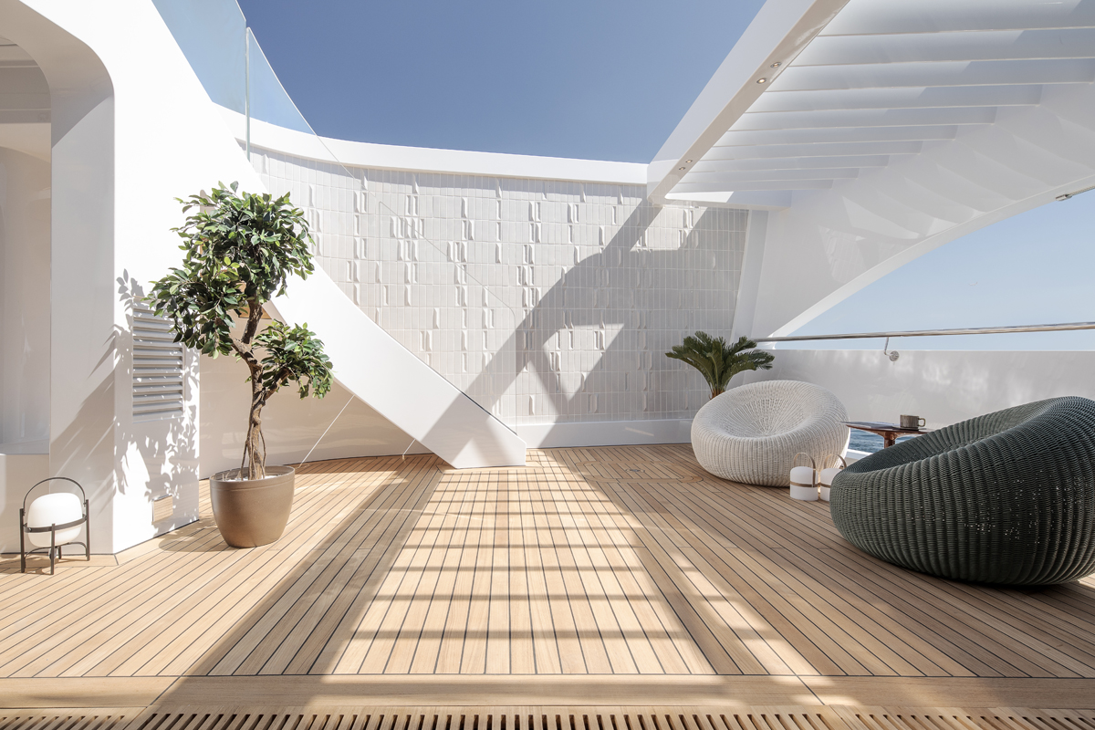 The Sirena 42M owner’s patio, with geometric white wall, planted tree, seating and pergola.