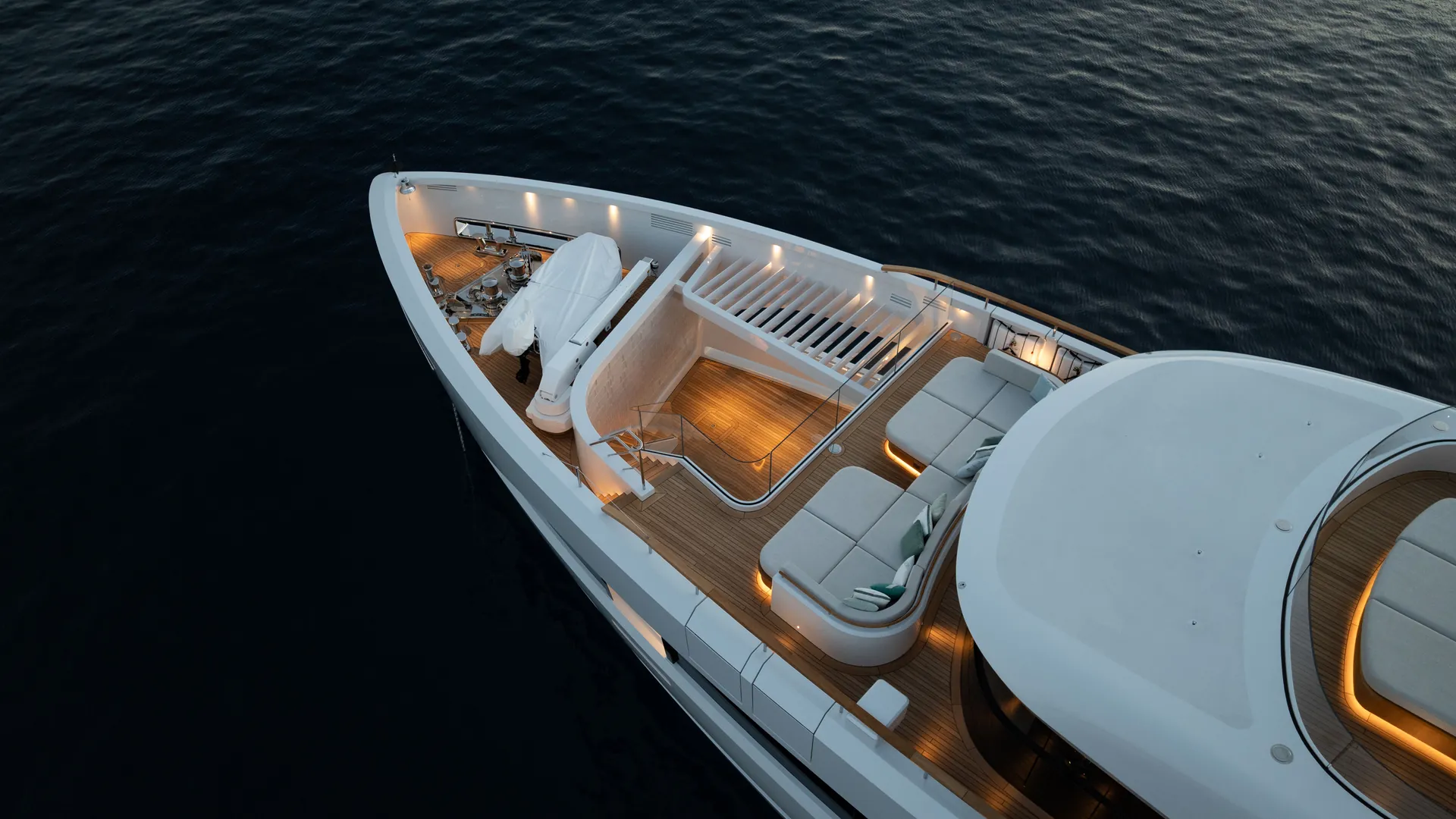 The Sirena 42M foredeck at dusk, with lighting around the courtyard and upper seating.