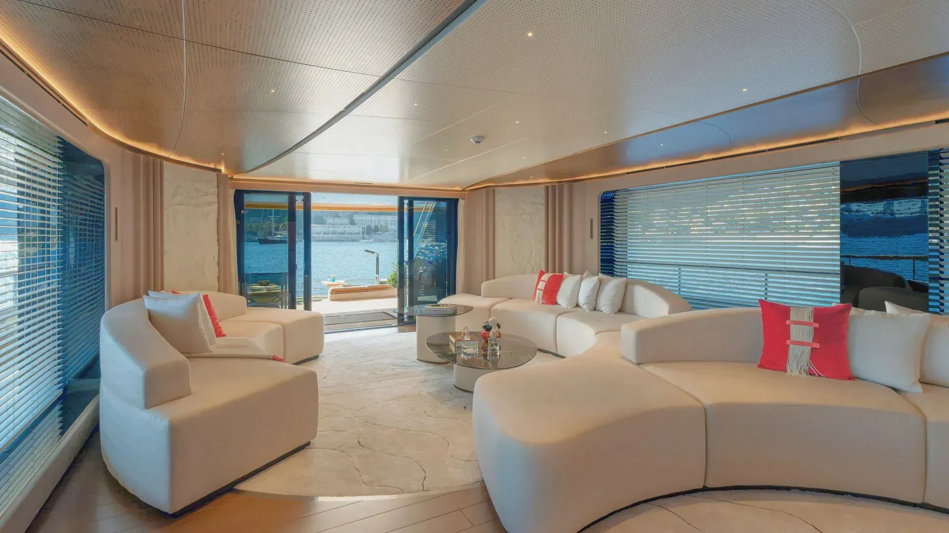 The Sirena 42M saloon with rounded sofas and low tables, looking towards the aft doors.